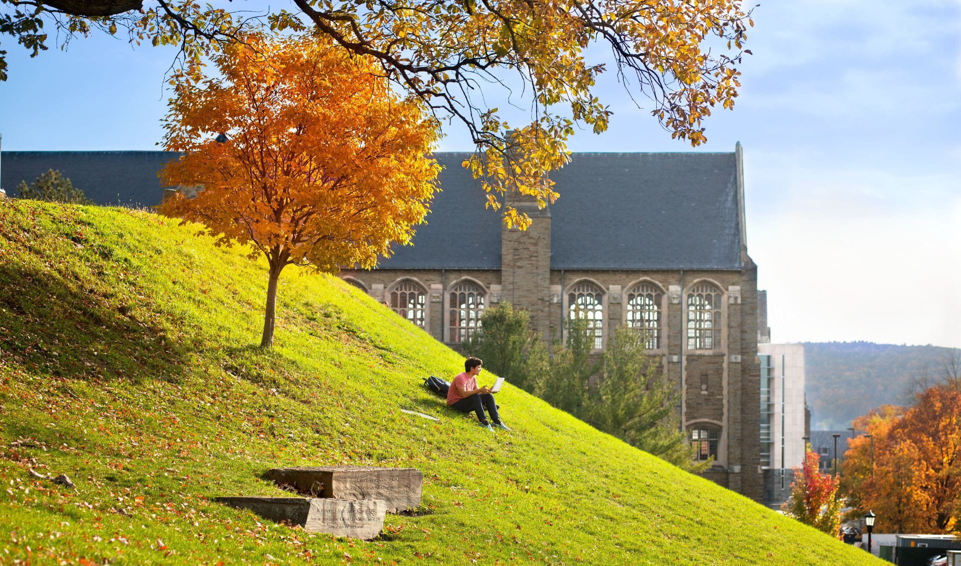 Student sitting on a hill on campus